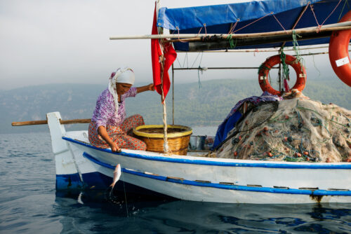 Mediterranean Conservation Society - Akdeniz Koruma Derneği - fisher woman fishing on a small boat carrying fisher nets
